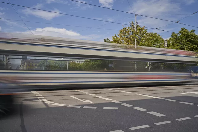 You can see a street being crossed by a tram. The tram is in motion and is therefore not in focus, but blurred.