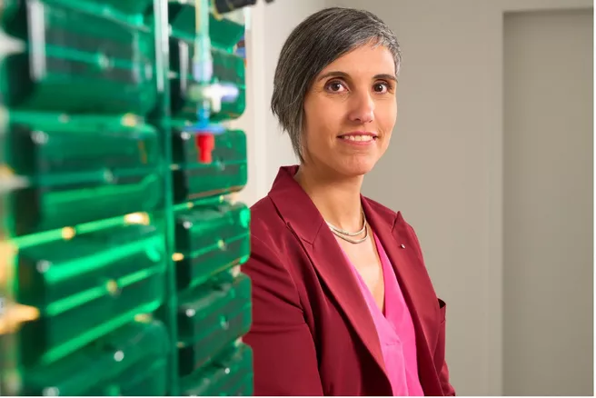 Portrait of Prof Gisela Detrell. Next to her you can see green boxes that probably contain algae. 